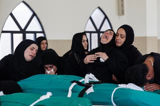 Relatives mourn over the bodies of four members of the Saeed family